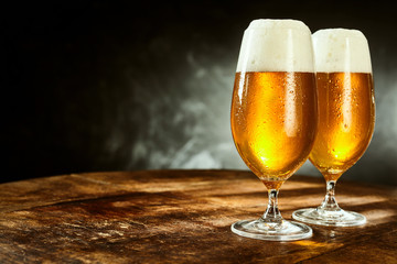 Two glasses full of beer on table - obrazy, fototapety, plakaty