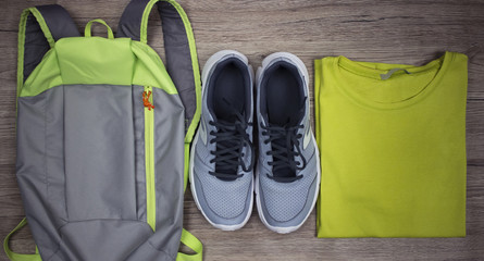Set for sports shoes, backpack, t-shirt close-up on a wooden background, top view