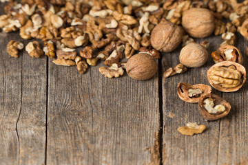 Walnut kernels and whole walnuts on rustic old wooden table