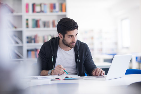 Student In School Library Using Laptop For Research