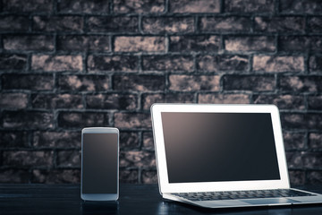 暗い部屋に置かれたラップトップとスマートフォン