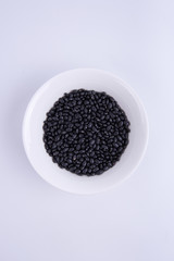 Black soybeans in white bowl on white background