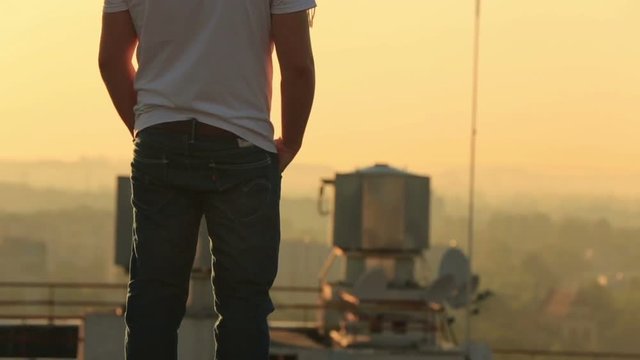Young handsome stylish man on the rooftop of skyscraper in industrial cityscape background