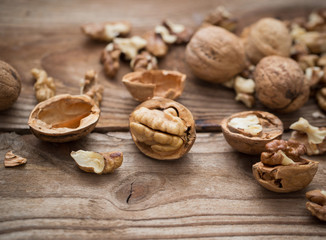 Fototapeta na wymiar Walnut kernels and whole walnuts on rustic old wooden table