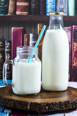 A bottle of rustic milk and glass of milk on a wooden table