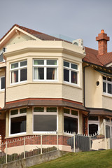 Modern two storey villa with vintage look behind white metal fence.