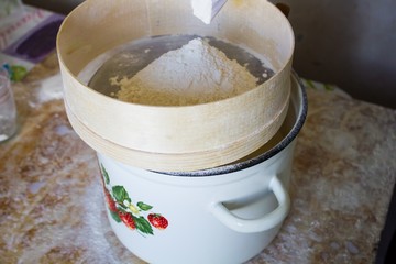 Flour is sifted through a wooden sieve 