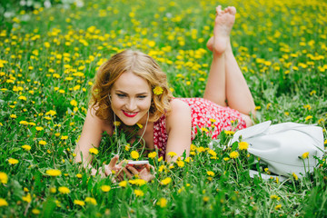 Naklejka na ściany i meble girl lying on the field in the dandelions and listening to music