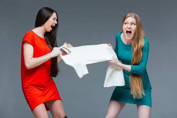 Two angry women quarreling and fighting for white dress