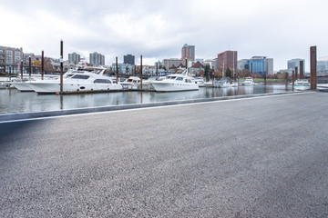 empty asphalt road near yacht with cityscape and skyline of port