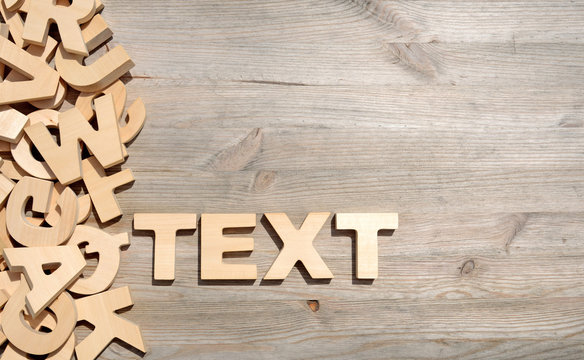 Word text made with block wooden letters next to a pile of other letters over the old wooden planks surface composition