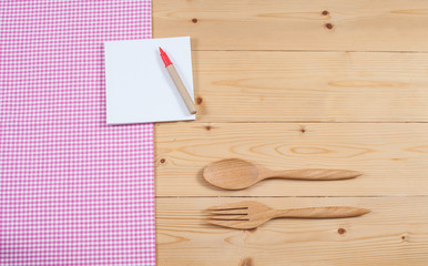 Tablecloth, wooden spoon, fork on wood textured background