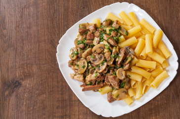 rigatoni pasta with meat and mushroom sauce in a plate on wooden table