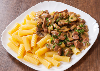 rigatoni pasta with meat and mushroom sauce in a plate on wooden table