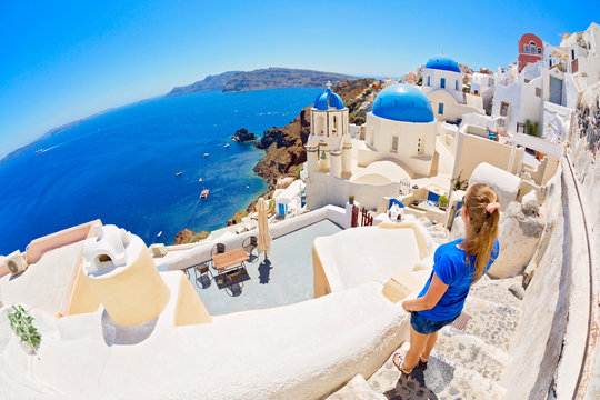 Luxury travel vacation woman looking at view on Santorini famous Europe travel destination. Elegant young lady living fancy jetset lifestyle wearing dress on holidays. Amazing view of sea and Caldera