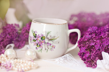 Obraz na płótnie Canvas a cup of tea or coffee with a pattern in lilac bouquet of lilacs