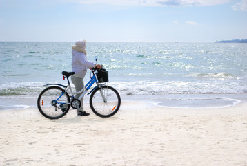 woman with a bicycle on the beach