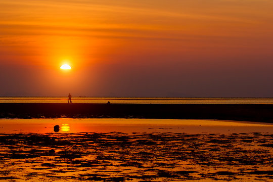 Silhouette of a man standing on the shallow seashore with his ki