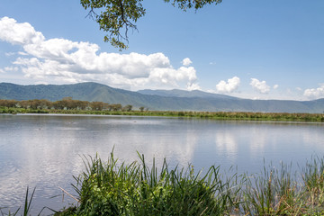 View on huge Ngorongoro caldera (extinct volcano crater) from within with large lake before against blue sky background. Great Rift Valley, Tanzania, East Africa.
