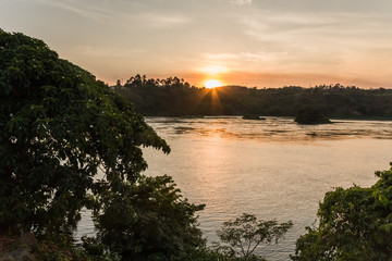 Fototapeta na wymiar Victoria Nile River at sunset with bright Sun reflecting in water against evening glow background. Jinja, Uganda, Eastern Africa. 