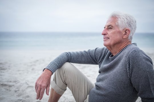 Thoughtful Retired Man Sitting On The Beach