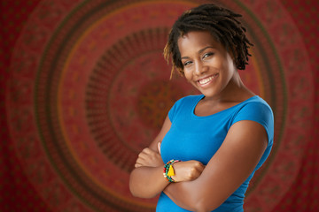 Happy young African-American woman standing with her arms crossed