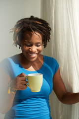 Smiling woman enjoying her morning coffee at window