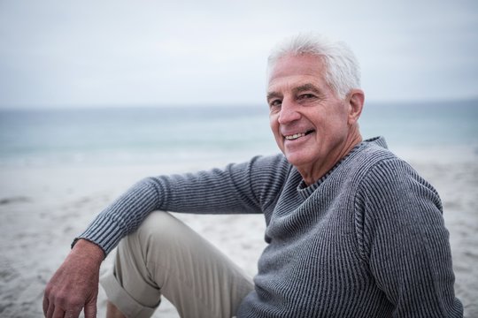 Happy senior man sitting on the beach