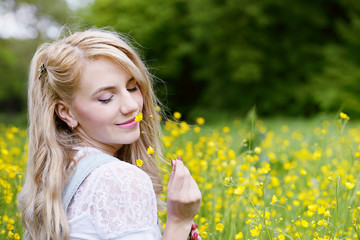 Beautiful blonde is smelling flowers