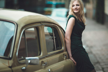 interesting girl standing near old car and looks to the camera