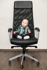 Little baby boy sitting on big chair