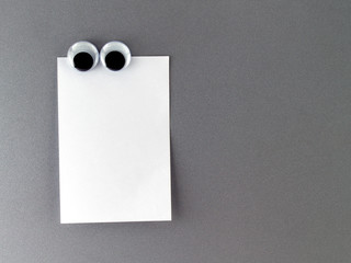 male eyes fridge magnet with blank note paper on grey refrigerator door