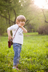 Adorable little kid boy with retro photo camera standing on a summer meadow on s sunny day. Outdoors. Young Photographer.
