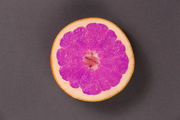 Bright pink fruit grapefruit top view. Pink greyfrut on a gray or black and white. Grapefruit in the center of the image. Grapefruit in the style of pop art.