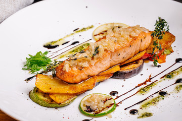 baked salmon with vegetables on glass plate isolated. Restaurant