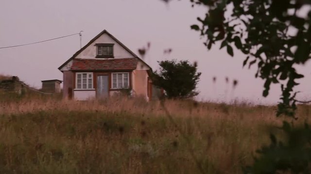 Lonely rural house standing on the  hill at sunset. Dolly shot.