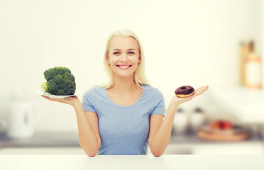 smiling woman with broccoli and donut on kitchen