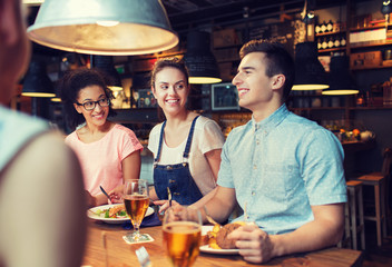 happy friends eating and drinking at bar or pub