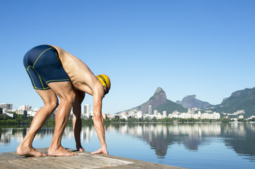 Athlete swimmer with yellow swimming cap crouching in the start position for a race at the Lagoa Rodrigo de Freitas lagoon in Rio de Janeiro, Brazil