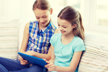 happy girls with tablet pc sitting on sofa at home