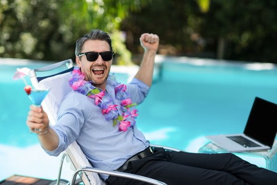 Excited man wearing garland and holding a martini glass