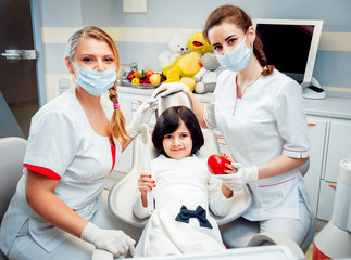 Little happy girl and two dentists