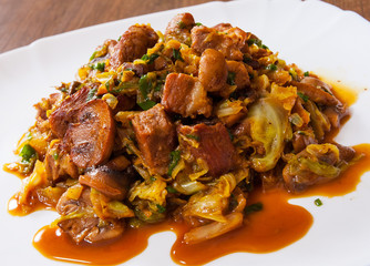 Stewed cabbage with mushrooms and meat in a plate on wooden table