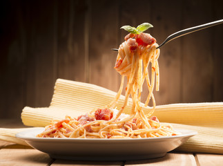 spaghetti with amatriciana sauce in the dish on the wooden table
