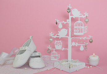 Baby girl shoes, candle and pearls pink background