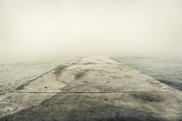 Stone pier in thick fog.