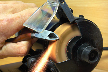Sharpening side cutting pliers on electrical grinding wheel