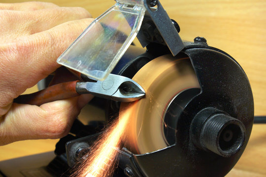 Sharpening side cutting pliers on electrical grinding wheel - Powered by Adobe