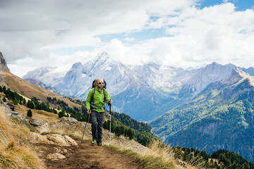 Fototapeta premium Man tourist with a backpack walking mountain trails in the Dolomite, Alps