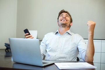 Smiling happy man holding mobile phone in office